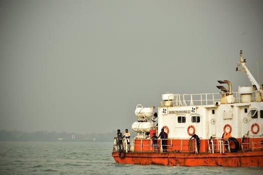 A nautical ship sailing on calm waters under a gloomy sky with visible crew members.