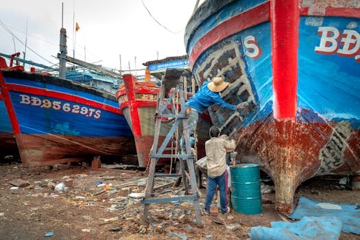 A group of men working together to repair fishing boats in a shipyard setting.