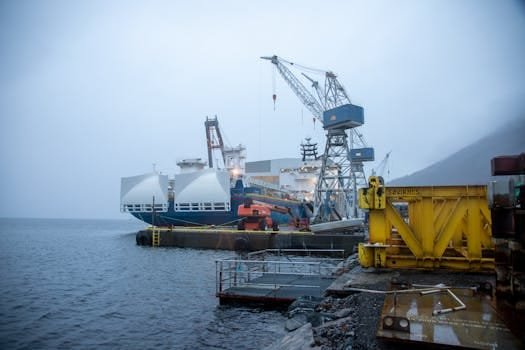 Angajări Capitani Vase și Echipaj Maritim 2026: Ghidul Complet pentru Joburi Offshore și Tehnicieni Nave 2 A misty boatyard scene in Norway featuring cranes and a large ship docked at the port.