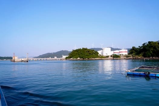Angajări Capitani Vase și Echipaj Maritim 2026: Ghidul Complet pentru Joburi Offshore și Tehnicieni Nave 3 A serene seascape featuring wind turbines and industrial structures on a sunny day.