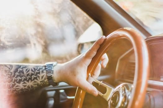 Close-up of tattooed hand on vintage car steering wheel in Asunción, Paraguay.