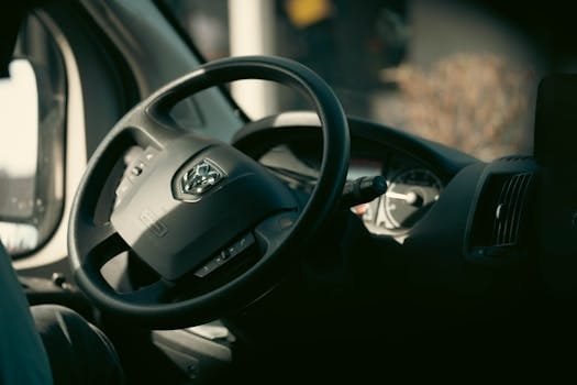 Detailed interior view of a vehicle showcasing the steering wheel and dashboard elements in soft lighting.
