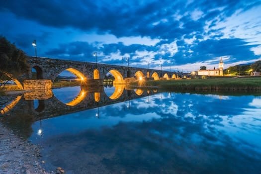 Historic bridge in Ponte de Lima beautifully reflected in the river during twilight in Portugal.