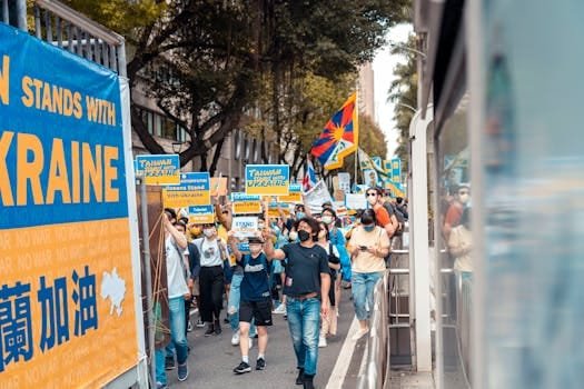 A vibrant protest supporting Ukraine with large crowd, banners, and colorful flags outdoors.