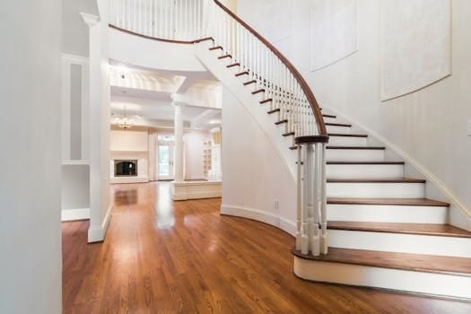Bright and spacious luxury home interior featuring a grand curved staircase and hardwood floors.