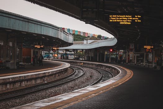 Urban train station with curved tracks and platform, featuring modern architecture.