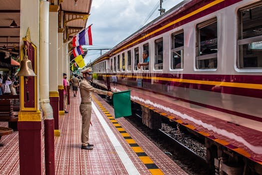 Conductor directing train at Ayutthaya Railway Station in Thailand, vibrant travel scene.