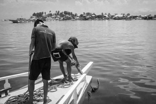 Întrebări Frecvente Platformă Joburi Maritime: Tot ce trebuie să știi despre carierele pe mare 3 Two fishermen on a boat docking at a pier in a calm sea.