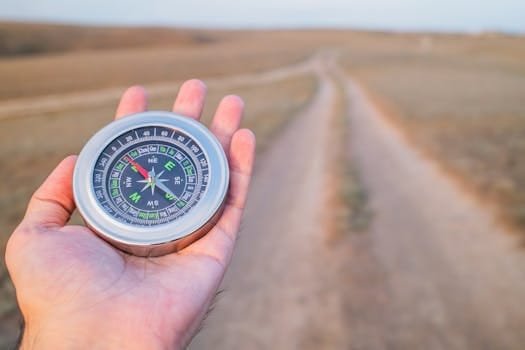 Hand holding a compass guiding along a dusty path outdoors. Perfect for travel and exploration themes.