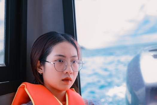 Young woman wearing glasses and lifejacket on a boat with ocean in background.