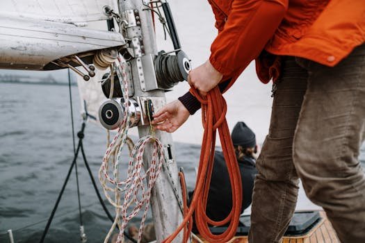 Close-up of a sailor handling ropes on a sailboat during a nautical expedition.