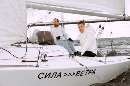 Two men sailing a yacht on a breezy day, showcasing teamwork and adventure.