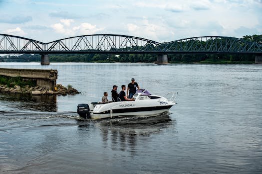 A group of people in a motorboat on a river, with a metal bridge in the background.