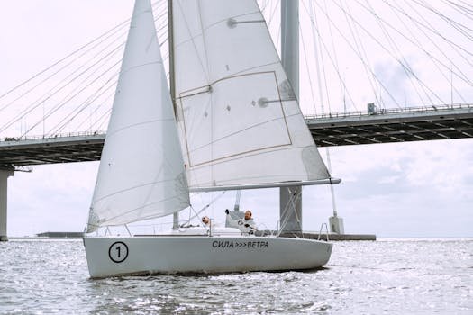 Sailboat navigating under a bridge on a calm day, showcasing the beauty of nautical adventure.
