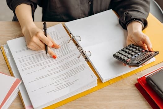 Cum să Obții un Certificat de Competență pentru Ofițerii de Punte și Mașină în România 4 A woman reviewing documents and using a calculator on a wooden table.