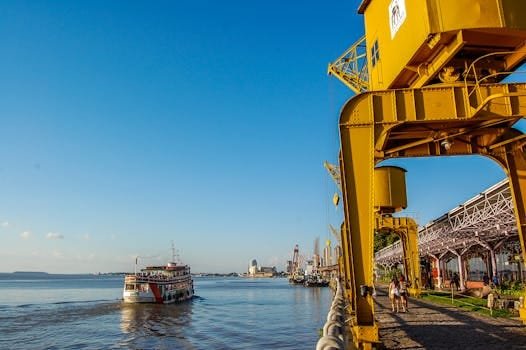 Vibrant harbor view with boat, crane, and people enjoying sunny weather.