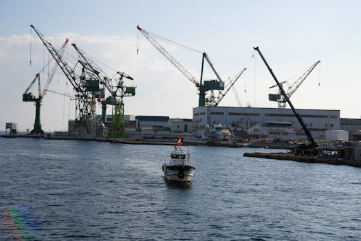 Probleme Frecvente în Contractele de Naviagție pentru Ofițeri de Punte și Cum să le Abordezi 4 View of Kobe port featuring large cranes and a boat navigating the waters, ideal for industrial themes.