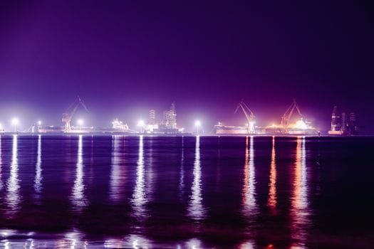 Cum să Alegi Între Crewing și Freelancing în Joburile Maritime și Impactul Asupra Salariilor 2 Long exposure photo of a harbor at night, featuring illuminated cranes and reflections on the water.