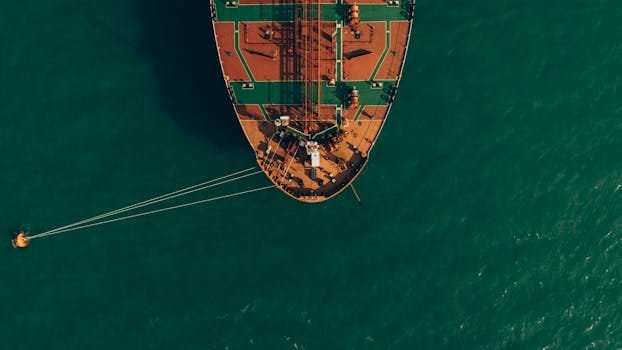 Top-down drone shot of a ship anchored in the calm Georgian Sea, showcasing vibrant hues and tranquil waters.