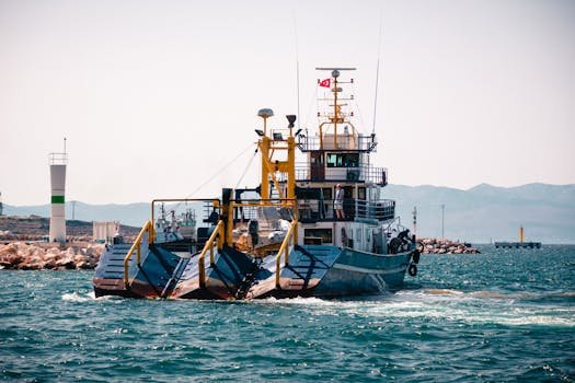 Cum să Obții Certificarea GMDSS și Să Avansezi în Cariera Maritimă din România 3 Large blue fishing boat with dredging equipment maneuvering in open waters near the coast.