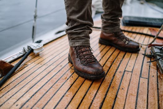 Cum să Obții un Contract de Muncă în Regim Ro-Ro ca Ofițer Punte Debutant 2 Close-up of rugged leather hiking boots standing on a wet wooden boat deck with ropes in view.