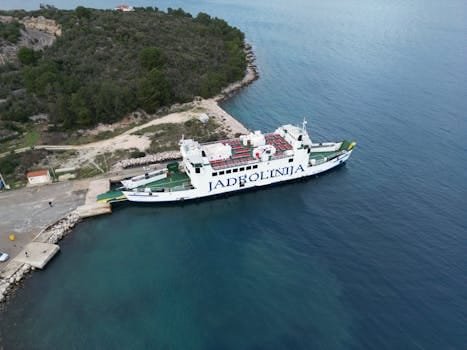 Cum să Optimizăm Diferența dintre Salariul Brut și Net în Contractele Ofițerilor Maritimi 4 Stunning aerial view of Jadrolinija ferry docked at Mali Iž in Croatia, surrounded by lush greenery and blue sea.