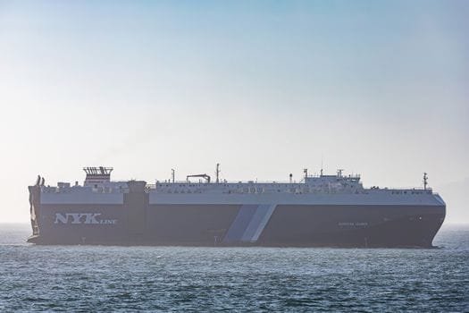 Ghid Complet: Cele Mai Bune Servicii de Recrutare Ofițeri Punte prin Agenții Crewing 3 A massive cargo ship traversing the calm sea under a clear sky.