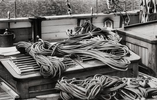 Top 5 Cursuri Certificare GMDSS Maritim pentru Frecvențe Radio: Alegerea Ideală 2 Black and white image of neatly coiled ropes on a vintage ship deck, showcasing maritime detail.