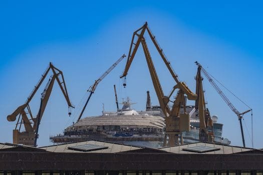 Scenic view of shipyard cranes surrounding a cruise ship under a clear blue sky in Cádiz, Spain.