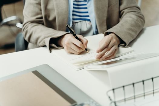 Alexandru și Drumul Crescător către un Contract Avantajos ca Ofițer de Mașină în Iulie 2026 2 Close-up of an adult writing in a notebook at a modern office desk, capturing professional planning.