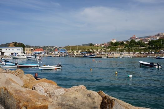 Ce Certificări sunt Esențiale pentru Marinarii Români care Caută Contracte de Navigație pe Timp de Vară 2026? 2 Picturesque scene of Tigzirt harbor with boats and coastal landscape under a clear sky.