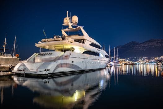 Cum a Găsit un Marinar Român Jobul Perfect în Sezonul Estival 2026 printr-o Agenție de Crewing 2 Elegant yacht reflecting in calm marina waters under a starry night sky.