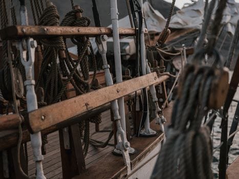 Detailed view of ropes and pulleys on a wooden boat deck with a vintage maritime feel.