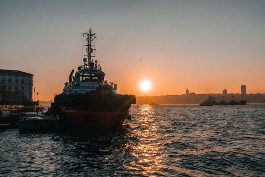 A stunning sunrise over Bosphorus Strait in Istanbul with a prominent tugboat and calm waters.