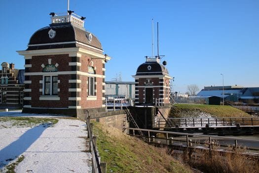 View of the historic Lemmer lock in Netherlands during winter with snow and blue skies.