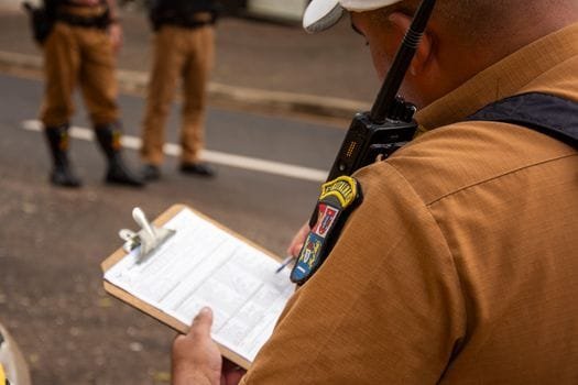 De ce Stabilitatea Joburilor Maritime pentru Ofițerii Români nu e un Mit în 2026 3 Close-up of a police officer writing on a clipboard outdoors in Londrina, Brazil.