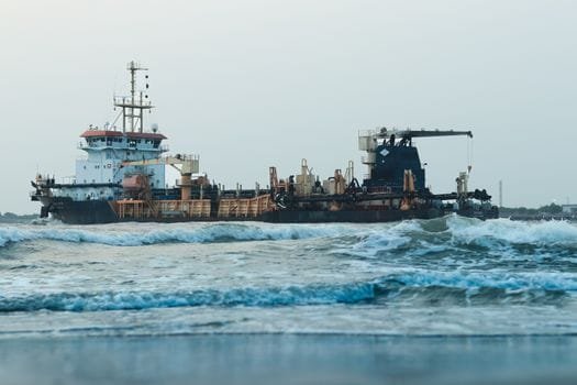Large cargo ship navigating through ocean waves in Kochi, India.