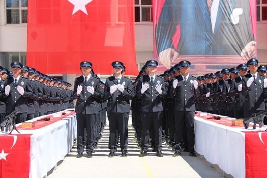 Police officers in uniform at a graduation ceremony in Yozgat, Türkiye with Turkish flags displayed prominently.