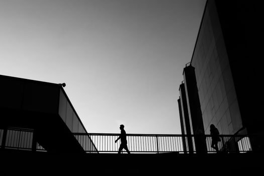 Silhouetted figures walking along a modern architecture pathway at twilight.