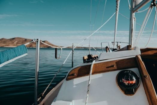 Experience tranquility aboard a sailboat with a clear sky and scenic coastal view.