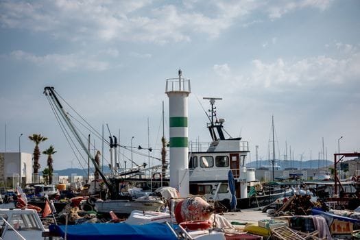 A bustling marina featuring boats, a lighthouse, and clear skies, capturing a vibrant nautical scene.