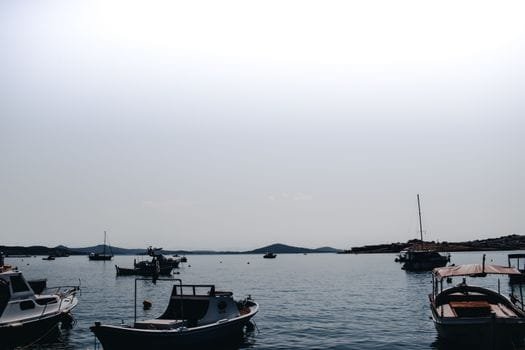 Moored boats floating peacefully on the sea in Ayvalık, Türkiye, under a clear summer sky.
