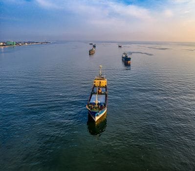 An aerial view of multiple cargo ships navigating the waters near Jakarta, Indonesia.
