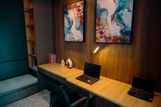 Captains jobs 3 Cozy office workspace in Jakarta with abstract art, laptops, and ambient lighting.