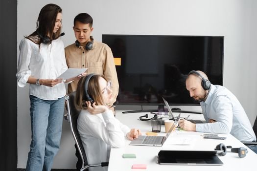 Captains jobs 4 Diverse team of professionals collaborating in a modern office with tech gadgets and headsets.