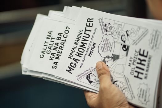 A stack of protest flyers in a hand, highlighting social issues and community concerns.