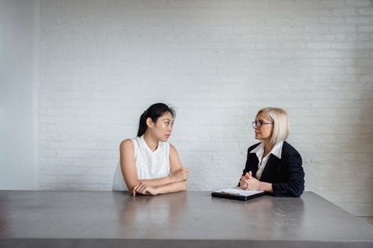 Cum și-a Găsit Ana un Înviorător Contract de Vară ca Ofițer de Mașină prin Agenții de Crewing din România, August 2026 4 Two women engaged in a business meeting in a white office setting, discussing serious matters.