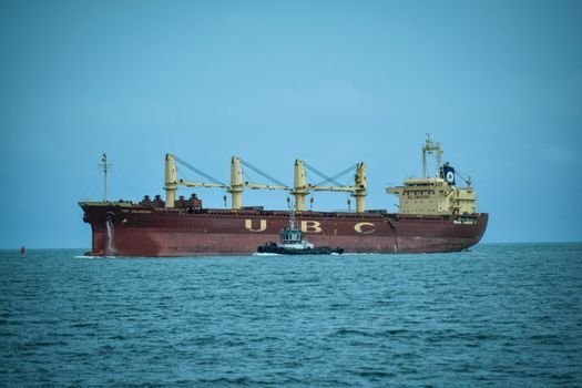Top 5 Poziții Entry Level în Navigație pentru Tinerii Marinari din România, August 2026 2 A cargo ship navigates the sea with a pilot boat in Veracruz, Mexico under a clear sky.
