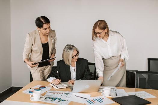 Ce Certificări Sunt Necesare pentru un 'Boat Officer' pe Nave Comerciale în România? 4 Three businesswomen discussing documents during a meeting in a modern office setting.