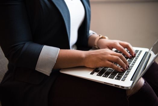 Cele Mai Importante 6 Certificări Navale pentru Cariera Ta pe Mare în Septembrie 2026 4 Woman in a blazer typing on a laptop in a well-lit room, focused on remote work.